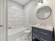 Modern bathroom features a tiled shower-tub combo, navy vanity, and a round mirror at 1449 Athens Sw Ave, Atlanta, GA 30310