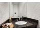 Stylish powder room features a granite countertop, oval sink, and patterned wallpaper at 3280 Stillhouse Se Ln # 305, Atlanta, GA 30339