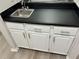 White wet bar with black countertop and stainless steel sink at 6146 Douglas Manor Ct, Douglasville, GA 30134