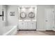 Spa-like bathroom with double vanity, hexagon mirrors, soaking tub, and natural light at 319 Pinewood Dr, Woodstock, GA 30189