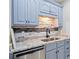Kitchen featuring granite countertops, stone backsplash, stainless steel dishwasher and light blue cabinets at 19 Spring Lake Trl, White, GA 30184