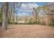View of the home's wooded and overgrown backyard with leaves covering the lawn at 3234 Bluebird Ln, Decatur, GA 30032