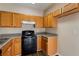 Bright kitchen with wood cabinets, black appliances, and laminate flooring at 3607 Ginnis Sw Dr # 7, Atlanta, GA 30331