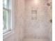 White tiled shower featuring a built-in shelf and a window at 43 Iroquois Ct, Covington, GA 30014