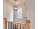Staircase featuring a wood banister and black iron spindles, lit by a decorative pendant light and natural light at 43 Iroquois Ct, Covington, GA 30014