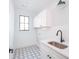 Bright laundry room with white cabinets, geometric tile floor, and modern sink at 89 1St Ne Ave, Atlanta, GA 30317