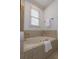 Bathroom featuring a soaking tub with tiled surround and natural light from a large window at 301 Fortune Ne St, Atlanta, GA 30312