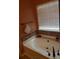 Oval bathtub with tile surround and window with blinds at 115 The Falls Blvd, Covington, GA 30016