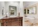 Bright bathroom featuring a wooden vanity, unique mirror, and a soaking tub with tiled surround at 1316 North Ne Ave, Atlanta, GA 30307