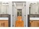 Dual sink bathroom featuring wood cabinetry, stone backsplash, and a hallway to a bedroom with a balcony at 273 12Th Ne St # 210, Atlanta, GA 30309
