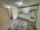 Compact kitchen with white cabinets, modern appliances, and sleek gray wood grain flooring at 305 Rampart St, Mcdonough, GA 30253