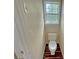 Powder room with toilet and small window, featuring hardwood style flooring at 305 Rampart St, Mcdonough, GA 30253