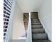 Carpeted staircase with a white banister leads upstairs, bathed in natural light from a nearby window at 305 Rampart St, Mcdonough, GA 30253