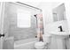 Bright bathroom featuring a white sink, toilet, and bathtub with gray tiled walls and a shower with patterned curtain at 1830 W Taylor Ave, Atlanta, GA 30344