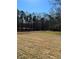 A spacious backyard with a mix of bare ground and emerging green grass, surrounded by mature trees at 4863 Amsler Rd, Ellenwood, GA 30294