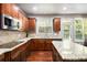 Bright kitchen featuring dark wood cabinets, stainless steel appliances, and a large granite countertop at 120 Fountain Oak, Villa Rica, GA 30180