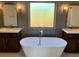 Luxurious bathroom with dual vanities, a standalone tub, and a large window for natural light at 1370 Long Acre Dr, Loganville, GA 30052
