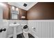Classic half bath features beadboard paneling, a pedestal sink, and dark brown accent wall for a stylish touch at 1131 Orr Rd, Jonesboro, GA 30238