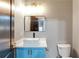 Well-lit bathroom with square sink on blue vanity and dark fixtures next to toilet at 3236 Tallon Sw Ln, Atlanta, GA 30311