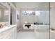 Bright bathroom featuring a soaking tub under a picture window, a glass shower stall and marble tiling at 3730 Ashford Ne Pt, Brookhaven, GA 30319