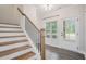 Inviting home entryway featuring wood stairs with black iron railings, white trim, and wood-look floors at 61 Harmony Woods Ln, Dallas, GA 30157