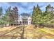 Beautiful rear exterior with large grassy yard, deck, mature trees, and professionally landscaped features at 4478 Outpost Ct, Roswell, GA 30075