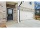 Front entry with dark gray door, brick facade, and attached two-car garage at 5539 Rosehall Pl, Atlanta, GA 30349