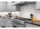 Stainless steel gas range and gray cabinets with white subway tile backsplash at 927 Amsterdam Ne Ave, Atlanta, GA 30306