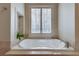Soaking tub with tile surround, shuttered window and plant accent at 305 Glengarry Chase, Covington, GA 30014