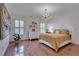 Bright bedroom featuring hardwood floors, chandelier, natural light from shuttered windows, and warm yellow bedspread at 305 Glengarry Chase, Covington, GA 30014