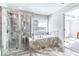 Bright bathroom boasts marble surround soaking tub, shower with glass door, and blind-covered window at 115 Greenbrier Way, Canton, GA 30114