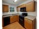 Galley kitchen with wood cabinets, black appliances, and laminate flooring at 720 Crestwell Sw Cir, Atlanta, GA 30331