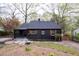 Classic home showcasing dark exterior with light framed windows, manicured landscaping, and natural surroundings at 2597 Elsinore St, East Point, GA 30344