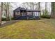 Charming, two-story home featuring a black exterior, brick chimney, and front yard with mature trees at 2597 Elsinore St, East Point, GA 30344