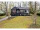 Charming, two-story home featuring a black exterior, brick chimney, and front yard with mature trees at 2597 Elsinore St, East Point, GA 30344