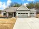 Gray craftsman style home with three car garage and rocking chairs on the front porch at 1018 Cherry Bark Ln, Loganville, GA 30096