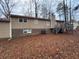 Tan house with a deck and stairs in a backyard with brown leaves at 6871 Lakeshore Dr, Douglasville, GA 30135