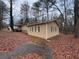 Tan house with black shutters and a side yard covered in brown leaves at 6871 Lakeshore Dr, Douglasville, GA 30135