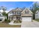 Charming two-story home featuring a stone and siding facade, covered porch with seating, and a two-car garage at 1102 Sweet Mia Ln, Powder Springs, GA 30127