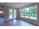 Dining area with a modern light fixture, hardwood floors, and a large window overlooking the landscaped yard at 5320 Memento Trace, Cumming, GA 30040