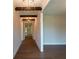 Long hallway with hardwood floors and accented with wooden beams and modern light fixtures at 5320 Memento Trace, Cumming, GA 30040