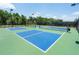 A community pickleball court in bright blue and green is surrounded by dark fencing and lush trees at 5320 Memento Trace, Cumming, GA 30040