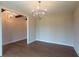 Neutral room with hardwood floors features stylish lighting and an open doorway to another room with wooden beams at 5320 Memento Trace, Cumming, GA 30040