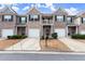 Charming townhomes with brick facade, individual garages, and inviting front entrances under a sunny, partly cloudy sky at 7174 Fringe Flower Dr # 21, Austell, GA 30168