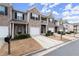 Row of townhomes featuring brick and siding, personal garages, and covered entrances, presented on a sunny day at 7174 Fringe Flower Dr # 21, Austell, GA 30168