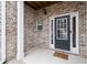Welcoming covered porch featuring a tiled floor, brick surround, and a charming front door, enhancing curb appeal at 7174 Fringe Flower Dr # 21, Austell, GA 30168