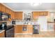 Kitchen with wood cabinets, stainless appliances, tile backsplash, tile flooring, and a view of the living room at 118 Gilberts Way, Temple, GA 30179