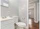 Bathroom featuring a toilet and sink with vanity adjacent to an open doorway with wood floors beyond at 3453 Eisenhower E Cir, Atlanta, GA 30354