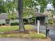 Well-maintained front yard features mature trees, an asphalt driveway, and a home with a covered carport at 104 Woodhaven Way, Alpharetta, GA 30009
