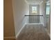 Hallway with neutral carpet and black metal railing leading to an adjacent bedroom at 2180 Highridge Point Dr, Lithia Springs, GA 30122